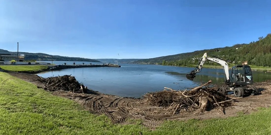 Gravemaskin ved vannkanten med opprensket strandsone