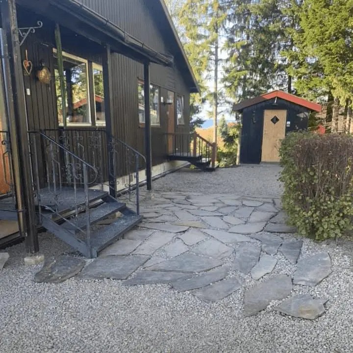 Inngangsparti med skiferheller lagt i grus ved et trehus